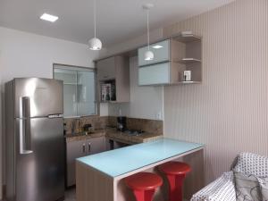 uma cozinha com um frigorífico e 2 bancos vermelhos em Apartamento Em Condominio Residencial Familiar em Cabo Frio
