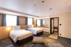 una camera d'albergo con due letti e uno specchio di Richmond Hotel Premier Tokyo Schole a Tokyo