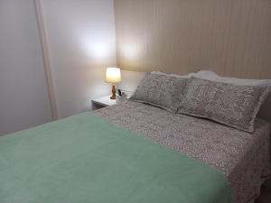um quarto com uma cama verde com uma almofada e um candeeiro em Apartamento Em Condominio Residencial Familiar em Cabo Frio