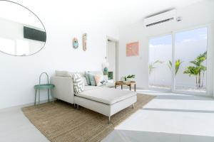 a white living room with a white couch and a window at Caya Erasmus 20 in Tanki Lender