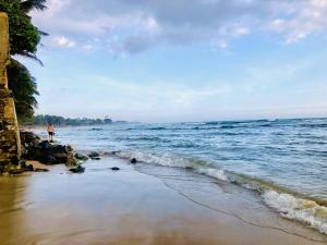a person standing on a beach near the ocean at Nilan Villa in Koggala