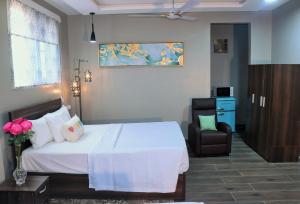 - une chambre avec un lit blanc et une chaise dans l'établissement Lady M guest House, à Tema