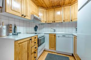 a kitchen with white appliances and wooden cabinets at Alppirinne - Tunnelmallinen loma-asunto Suomulla in Suomutunturi