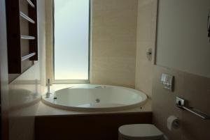 a bathroom with a tub and a toilet and a window at Sea Art Hotel in Vado Ligure