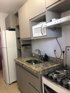 a kitchen with a sink and a stove and a refrigerator at Apartamento próximo ao Parque e Aeroporto - com academia e piscina in Uberlândia