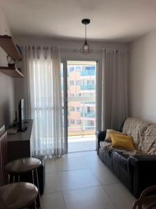 a living room with a couch and a large window at Apartamento próximo ao Parque e Aeroporto - com academia e piscina in Uberlândia