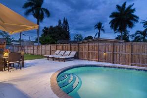 a swimming pool with chairs and a table and a fence at Beachway Per ankh (House of Life) in Pompano Beach