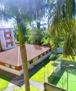 a palm tree in front of a house at Apartamento TOP CLIMATIZADO em CRICIÚMA-SC - ótimo CUSTO-BENEFÍCIO - Cozinha completa - Cama Box - WiFI - Smart TV - Apps YouTube - NetFlix - Prime Vídeo - Garagem coberta - Portaria Digital 24h - Lugar sossegado e arborizado - Acomoda até 5 pessoas in Criciúma
