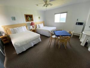 Cette chambre comprend 2 lits, une table et un lavabo. dans l'établissement Restaurant-Motel L'Etoile du Nord, à Pointe a la Fregate