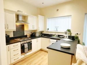 a kitchen with white cabinets and a black counter top at Townhouse close to Liverpool City Centre - 4 bedrooms in Liverpool