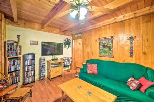 a living room with a green couch and wooden walls at Cozy Tellico Plains Cabin with Large Mountain Creek! in Tellico Plains