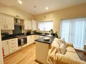 a kitchen with white cabinets and a couch in a room at Townhouse close to Liverpool City Centre - 4 bedrooms in Liverpool
