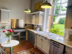 een keuken met een fornuis en een tafel met een vaas met bloemen bij Stunning Countryside Home with Hot Tub - Sleeps 8 in Thurgarton