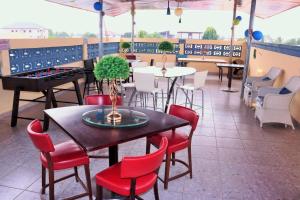 un restaurant avec des tables, des chaises rouges et une table avec une plante dans l'établissement Lady M guest House, à Tema