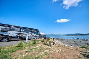 un wagon garé à côté d'un lac avec une clôture dans l'établissement Narrows Too Camping Resort Loft Cottage 12, à Trenton
