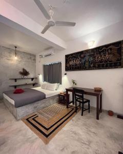 a bedroom with a bed and a desk and a ceiling fan at Namaste Jungle - A Boutique Homestay in Assagao