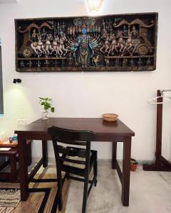 a wooden table with a chair and a painting on the wall at Namaste Jungle - A Boutique Homestay in Assagao