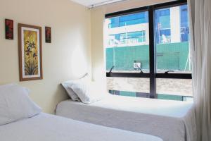 um quarto com 2 camas e uma janela em Apartamentos na Orla da Pajuçara em Maceió