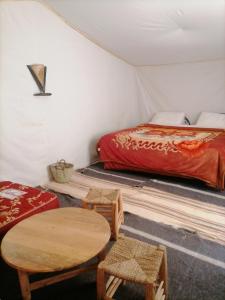 a room with a bed and a table and chairs at Erg Chegaga Desert Night in El Gouera