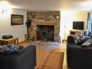a living room with two couches and a stone fireplace at Georges Cottage - Hsss in Clovelly