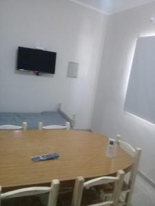 mesa de madera con 2 sillas y TV en la pared en Departamento DYD JUJUY en San Rafael