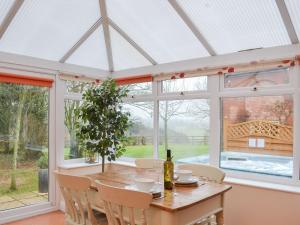 a conservatory with a wooden table and chairs and windows at The Old Winery Cottage in Dymock