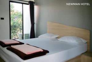 a large white bed with two pillows and a window at Newman hotel in Ban Khlong Ha