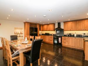 una cocina con mesa de comedor y una cocina con armarios de madera. en The Granary, en Chepstow