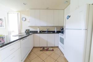 a kitchen with white cabinets and a white refrigerator at Bird of Paradise Condo in Kahuku