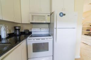 a kitchen with white appliances and a white refrigerator at Bird of Paradise Condo in Kahuku