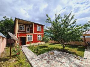 ein rotes Haus mit einem Baum im Hof in der Unterkunft Gabala red villa in Qəbələ