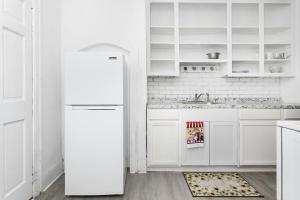 a white kitchen with white cabinets and a refrigerator at A cozy home with fire place in Detroit