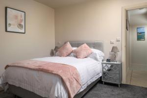 Un dormitorio con una cama con almohadas rosas. en Cartref en Benllech