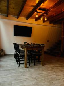 a dining room with a table with chairs and a flat screen tv at Hidden Cabin in Brezoi