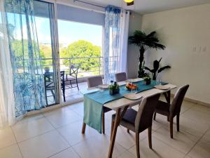 een eetkamer met een tafel en stoelen en een balkon bij OASIS Penthouse with private garden & shared pool in Koolbaai