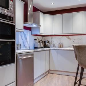 una cocina con armarios blancos y electrodomésticos de acero inoxidable en Somerset House en Bangor