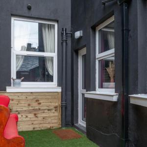 a black house with two windows and a red chair at Somerset House in Bangor