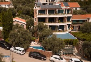 un edificio con coches estacionados en un estacionamiento en Apartments and Rooms Levantin Inn, en Sveti Stefan