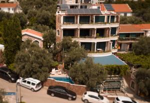 a building with cars parked in a parking lot at Apartments and Rooms Levantin Inn in Sveti Stefan
