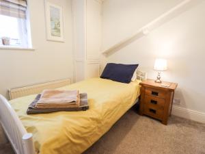 a small bedroom with a yellow bed with a night stand at Thames Cottage in Hull
