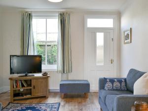 a living room with a tv and a blue couch at 14 Greta Villas in Keswick