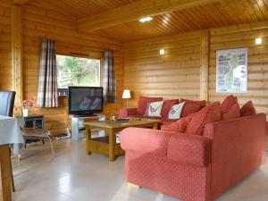 een woonkamer met een rode bank en een tv bij Cider Mill Lodge - Hw7420 in Tintern