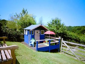 una pequeña cabaña azul con un paraguas y una valla en Woodland View - Hmr, en Combe Martin