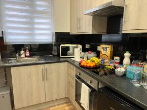 a kitchen counter with a bowl of fruit on it at JJ Serviced Apartment - Close to Tube Station & Near Central London & Wembley in Northolt