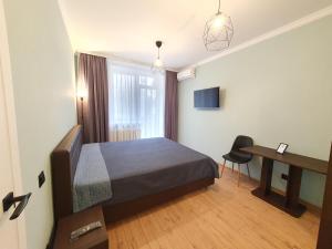 a bedroom with a bed and a desk and a window at All New and Cozy Apartment in the Silence Center in Chişinău