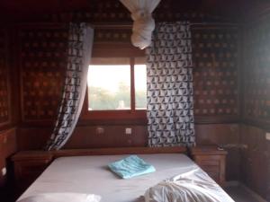 Bett in einem Zimmer mit Fenster in der Unterkunft Maison de Vacances à Foundiougne, Sénégal in Poundiougne