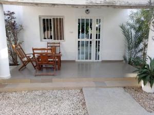 - une terrasse couverte à l'avant d'une maison blanche avec une table et des chaises dans l'établissement Maison de Vacances à Foundiougne, Sénégal, à Poundiougne