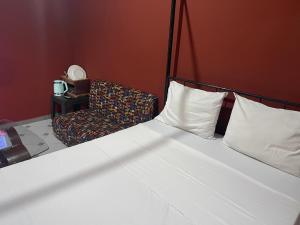 a bedroom with a white bed and a chair at Keur Karim sarr chambre d hôtes in Mbour