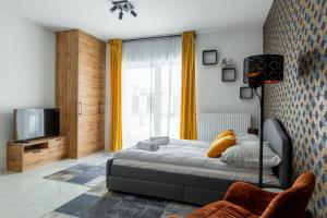 1 dormitorio con 1 cama, TV y cortinas amarillas en Apartament Ażurowy, en Kudowa-Zdrój