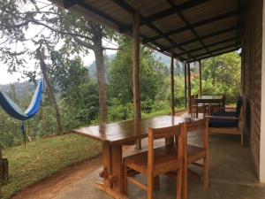 una mesa de madera y sillas en un porche con hamaca en Milemeleni Guesthouse, en Lushoto